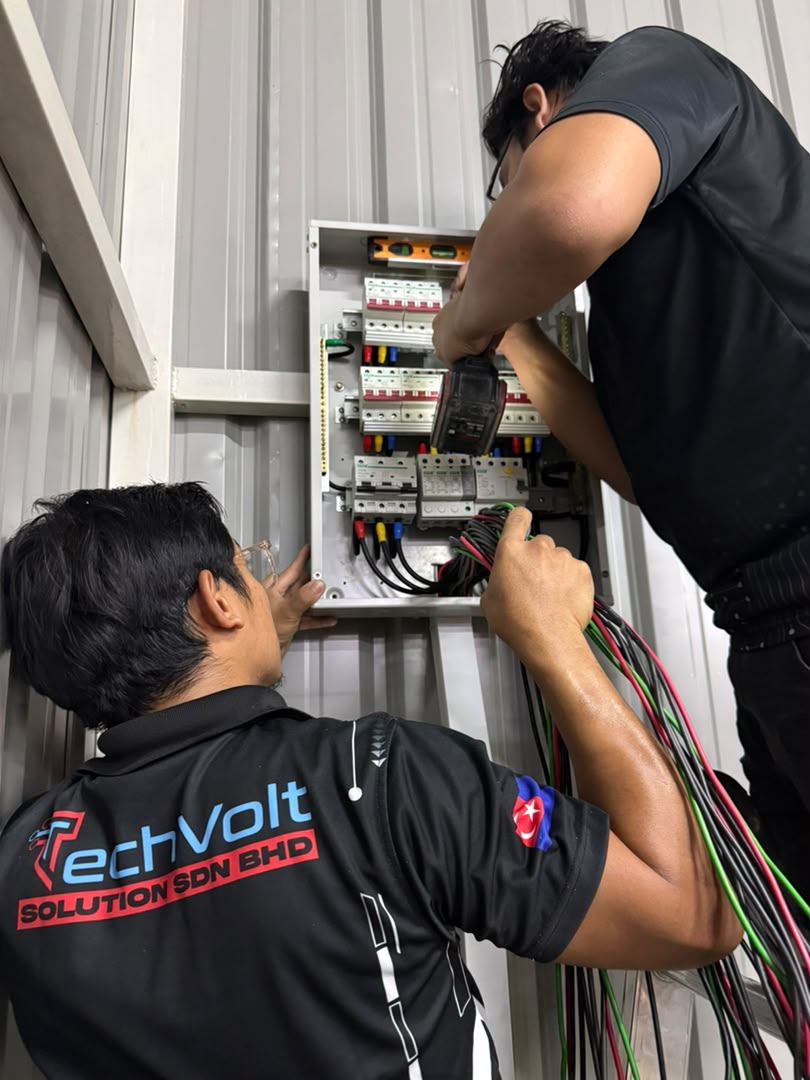 Two TechVolt technicians wiring a panel